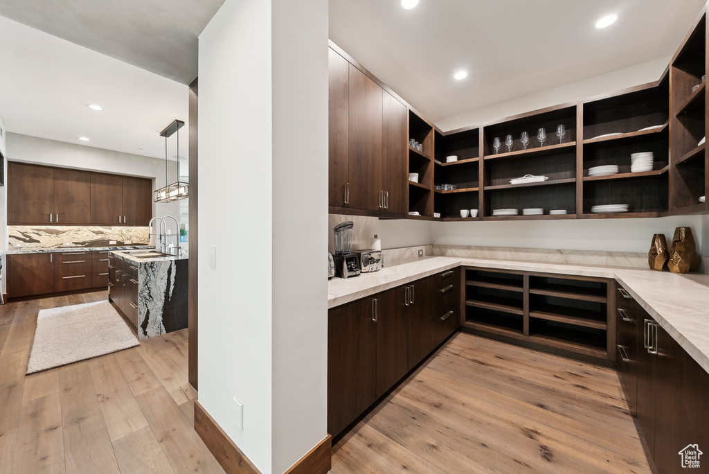 Kitchen with dark brown cabinets, open shelves, light wood-style floors, recessed lighting, and tasteful backsplash