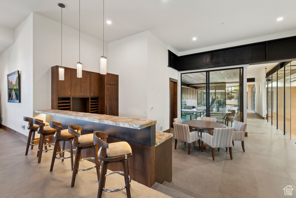 Kitchen featuring a kitchen bar, pendant lighting, recessed lighting, light countertops, and modern cabinets