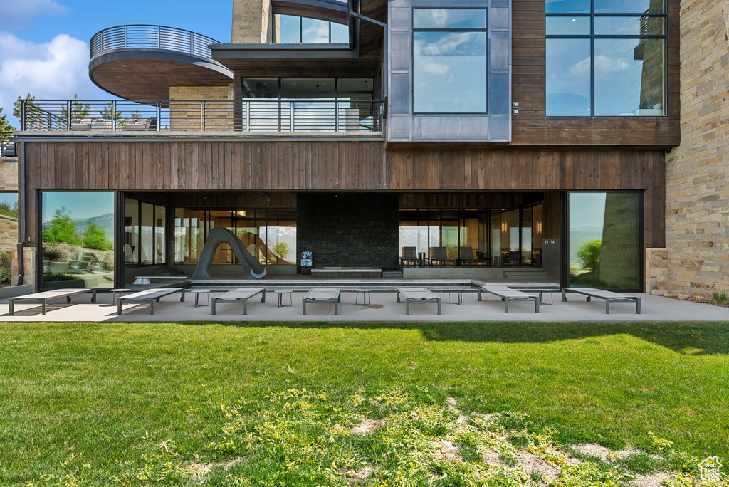 Rear view of property featuring a patio area, a yard, and a balcony