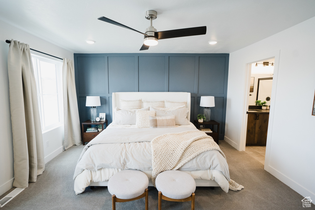 Bedroom with a decorative wall, ceiling fan, baseboards, and light carpet