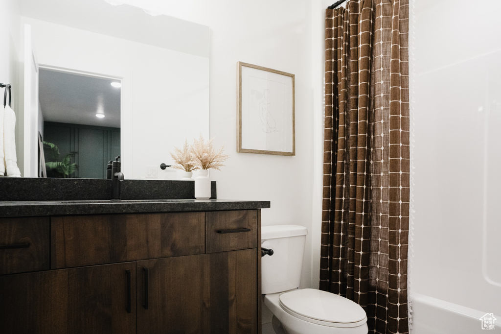 Bathroom with toilet, vanity, and shower / tub combo with curtain