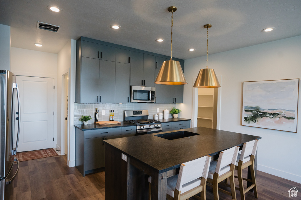 Kitchen featuring appliances with stainless steel finishes, dark countertops, dark wood finished floors, backsplash, and baseboards