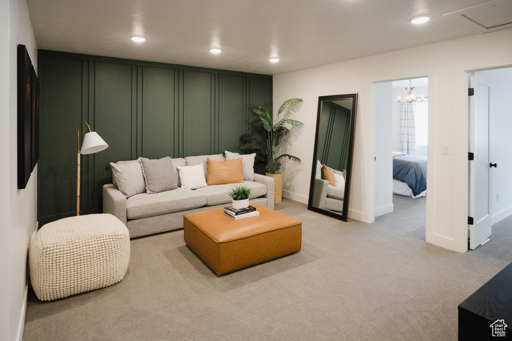 Living room with recessed lighting, a decorative wall, light carpet, baseboards, and a chandelier