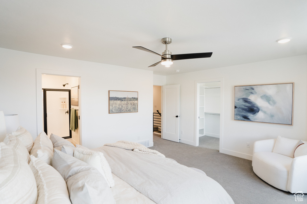 Bedroom with a walk in closet, light carpet, baseboards, a ceiling fan, and ensuite bath