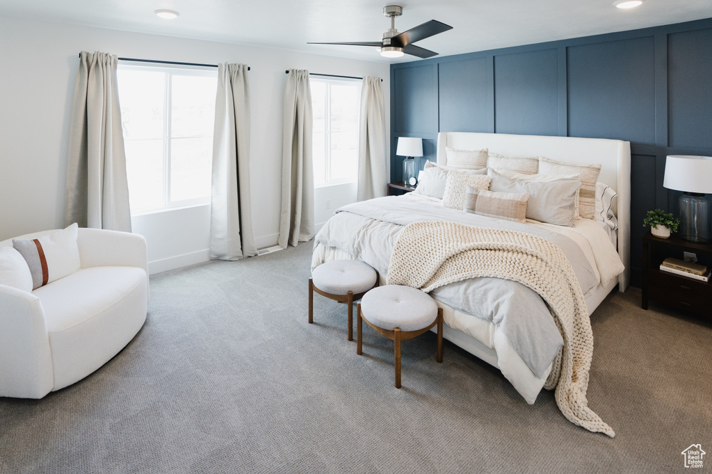 Bedroom featuring light colored carpet, a decorative wall, and ceiling fan