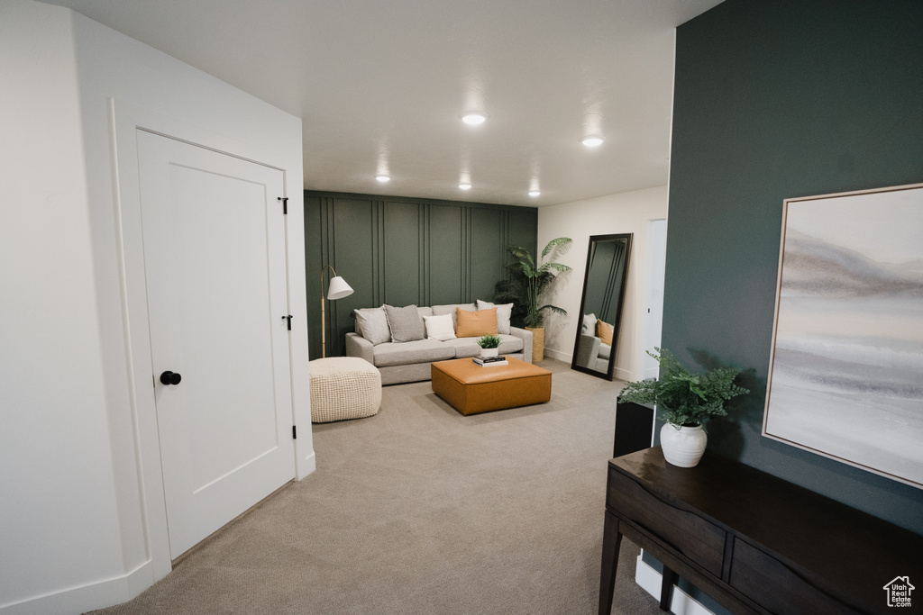 Living room with a decorative wall, carpet floors, and recessed lighting