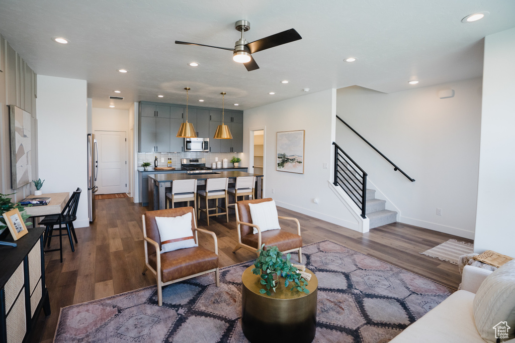 Living room with stairs, dark wood-style floors, a ceiling fan, recessed lighting, and baseboards