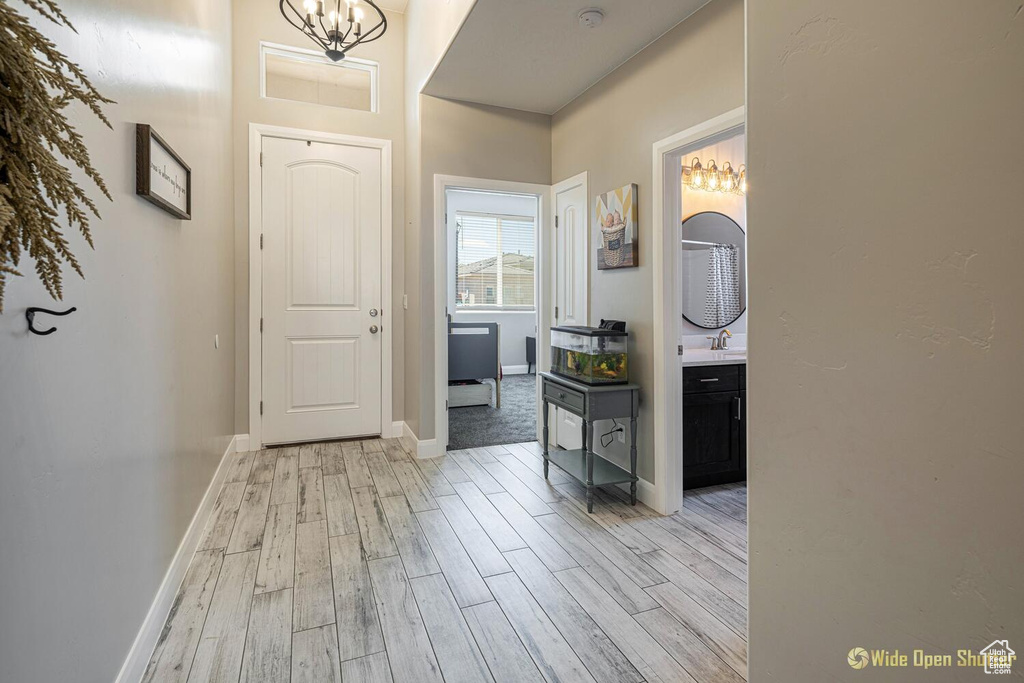 Foyer with light wood-style flooring, a chandelier, and baseboards
