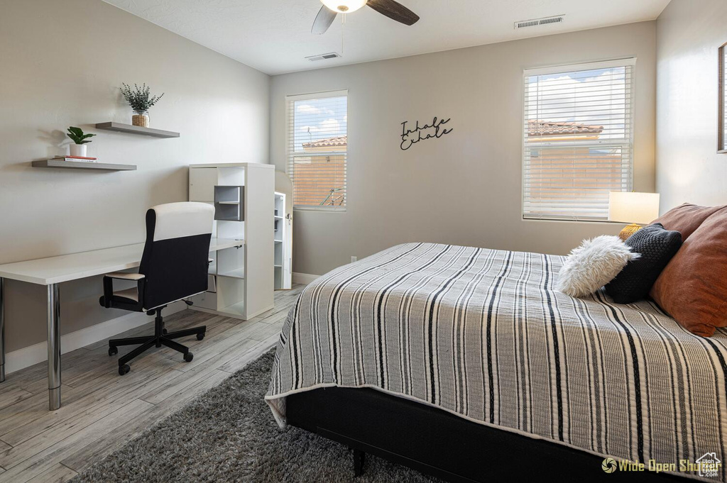 Bedroom with light wood finished floors, a desk, baseboards, and ceiling fan
