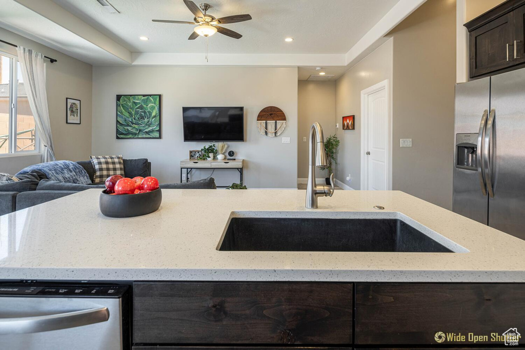 Kitchen with open floor plan, appliances with stainless steel finishes, a sink, dark brown cabinets, and a ceiling fan