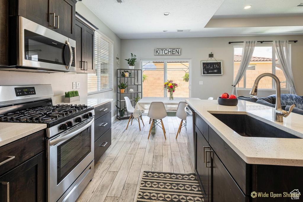 Kitchen featuring stainless steel appliances, a sink, light wood-style flooring, recessed lighting, and light stone countertops