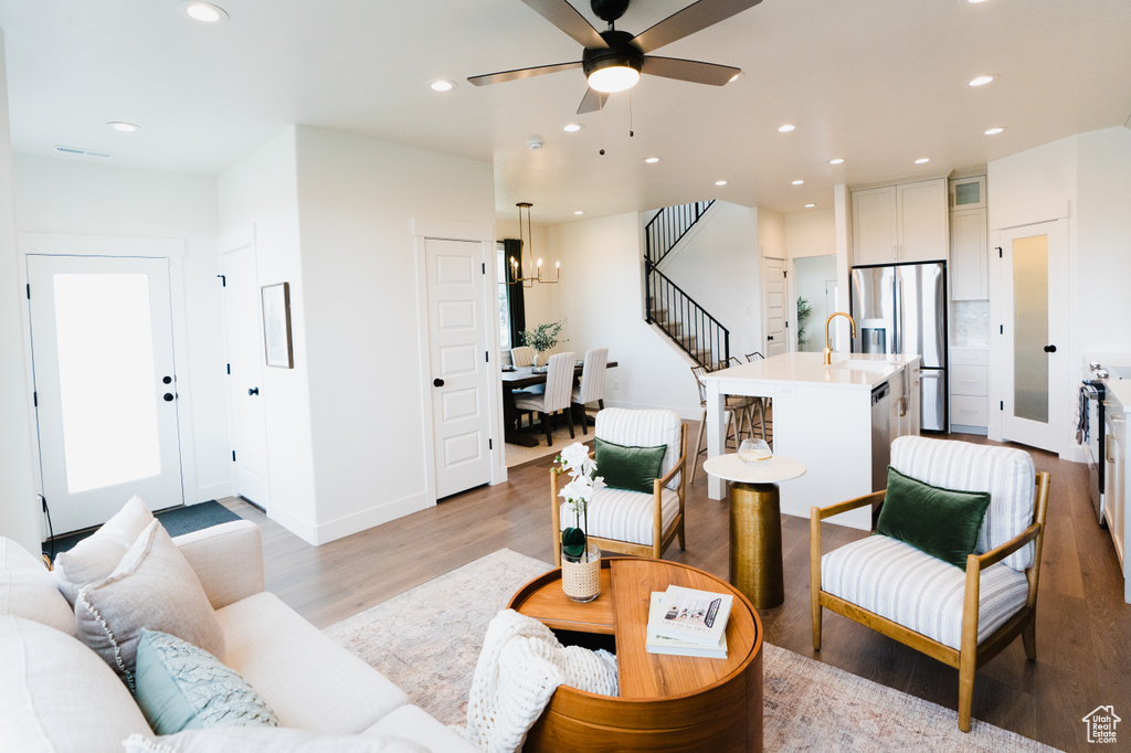 Living room featuring light wood-type flooring, recessed lighting, stairs, a ceiling fan, and baseboards