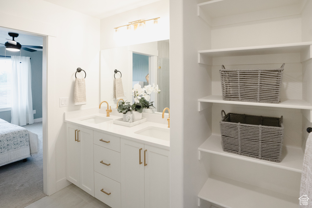 Full bathroom with double vanity, ensuite bathroom, a ceiling fan, tile patterned flooring, and baseboards