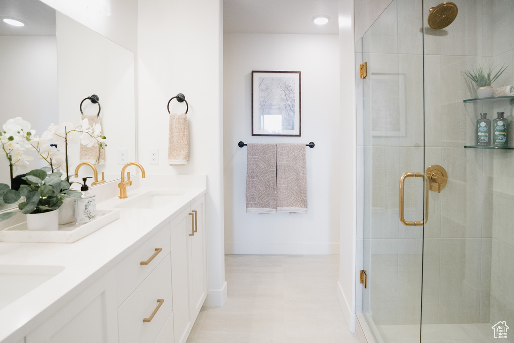 Full bathroom with a shower stall, double vanity, and baseboards
