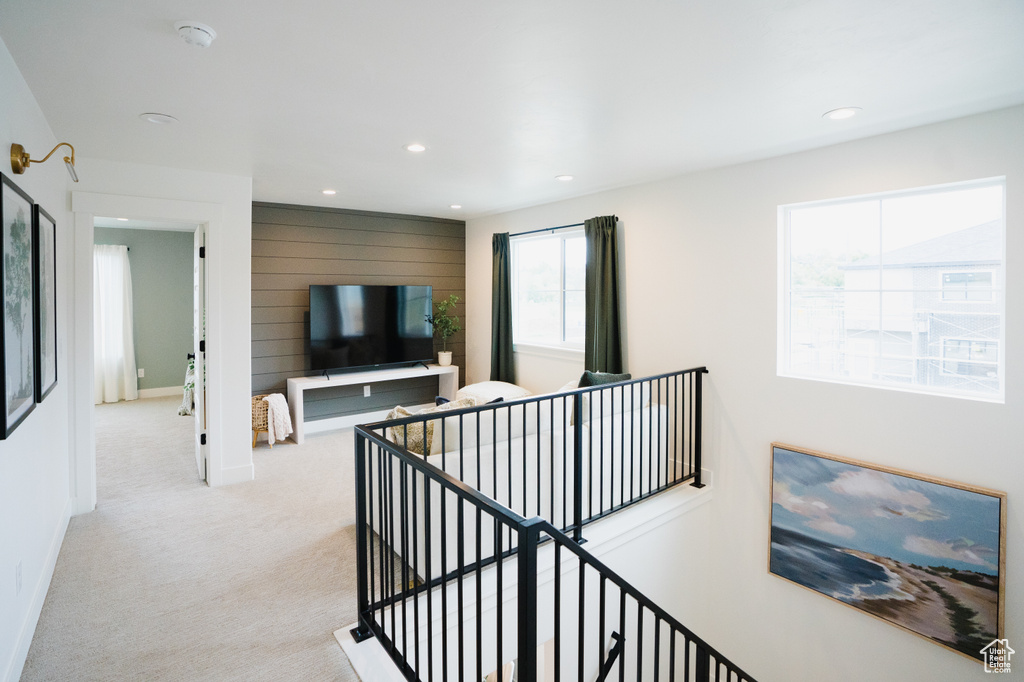 Hall with an upstairs landing, light colored carpet, baseboards, recessed lighting, and wooden walls