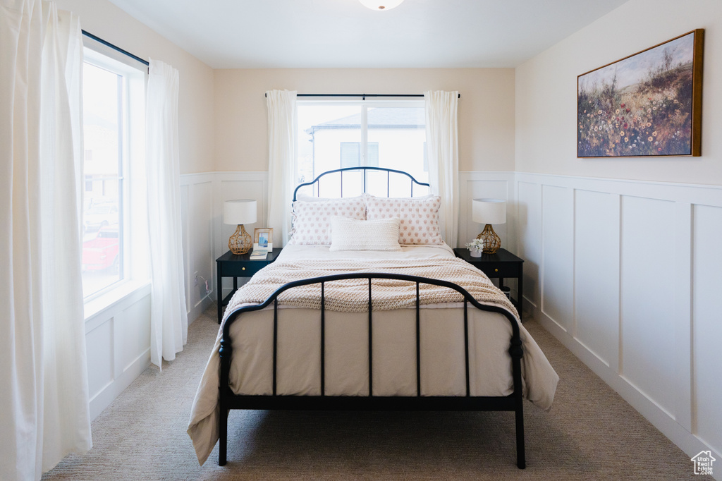Bedroom with a decorative wall, carpet, and wainscoting