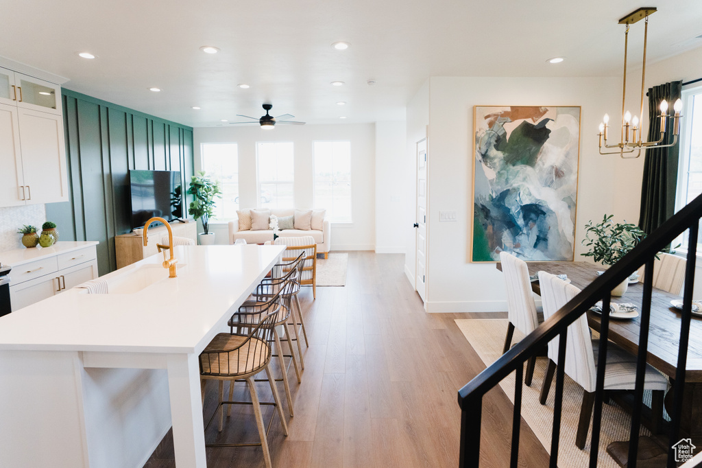 Kitchen featuring a sink, a breakfast bar area, light wood-style flooring, a chandelier, and light countertops