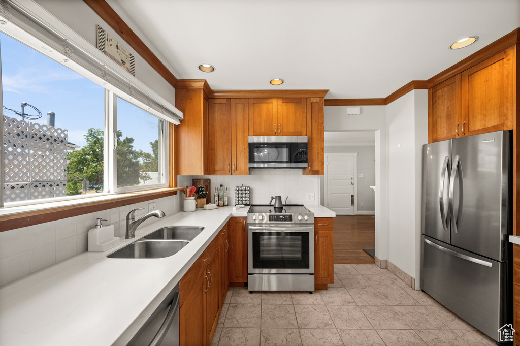 Kitchen featuring stainless steel appliances, a sink, decorative backsplash, brown cabinets, and recessed lighting