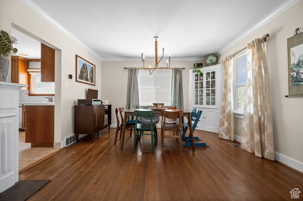 Dining space featuring a chandelier, wood finished floors, crown molding, and baseboards