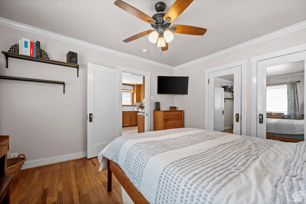 Bedroom featuring baseboards, light wood finished floors, ornamental molding, a ceiling fan, and ensuite bath