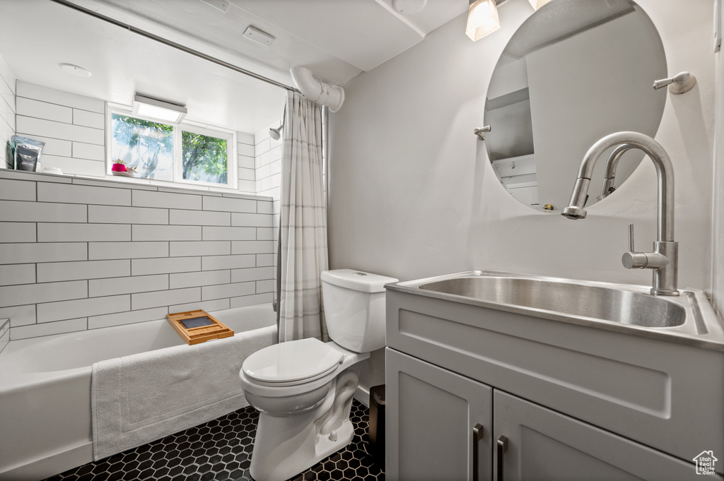 Full bathroom featuring toilet, shower / bathtub combination with curtain, and vanity