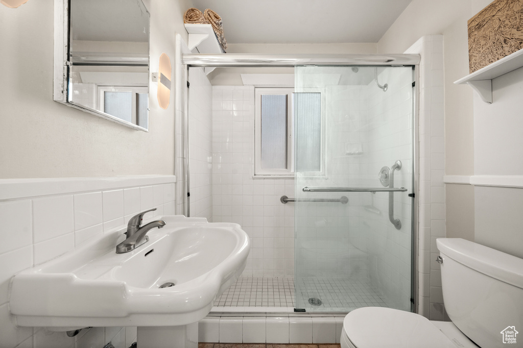 Full bath with toilet, a shower stall, and tile walls