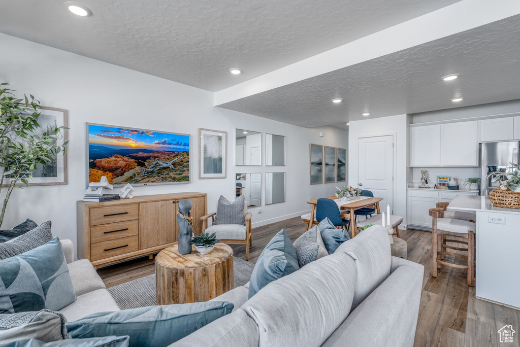 Living room featuring a textured ceiling, wood finished floors, recessed lighting, and baseboards