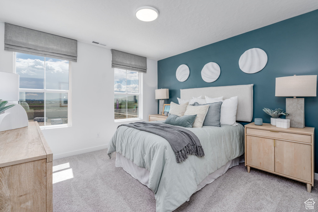 Bedroom featuring light carpet, multiple windows, and baseboards