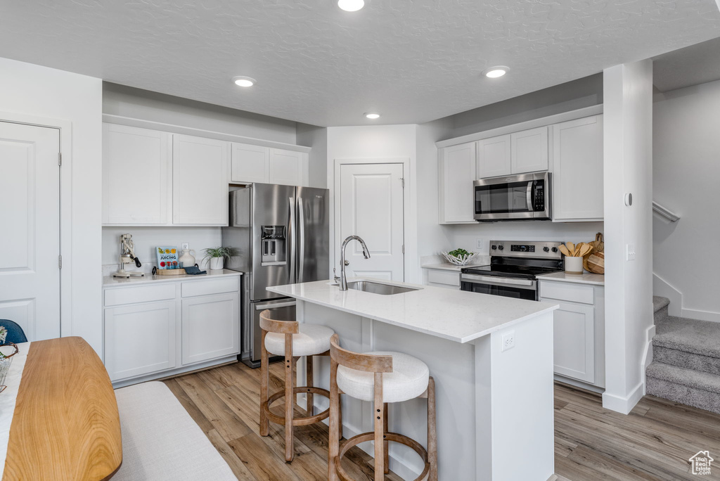 Kitchen featuring appliances with stainless steel finishes, a sink, light wood-type flooring, white cabinets, and recessed lighting