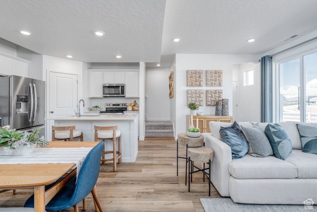Living area with light wood finished floors, recessed lighting, and a textured ceiling