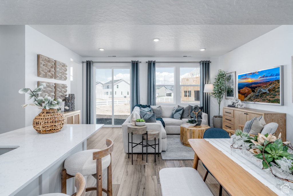Living area with light wood-style flooring, a textured ceiling, and recessed lighting
