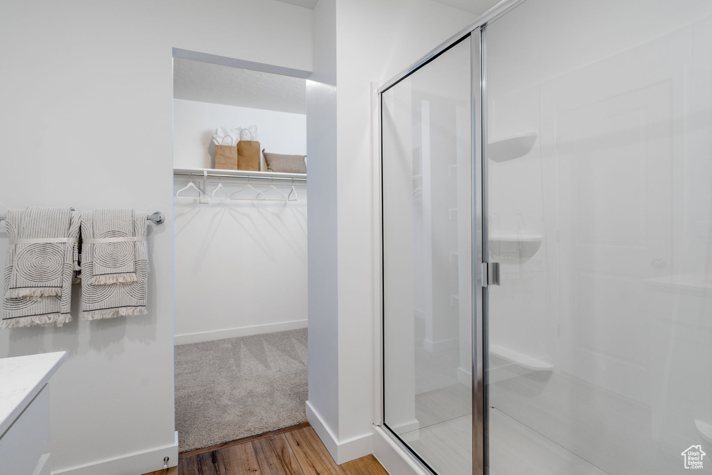 Bathroom with a shower stall, a spacious closet, wood finished floors, and vanity