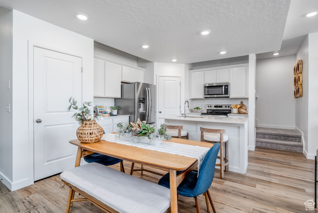Dining area featuring light wood finished floors, recessed lighting, stairway, baseboards, and a textured ceiling