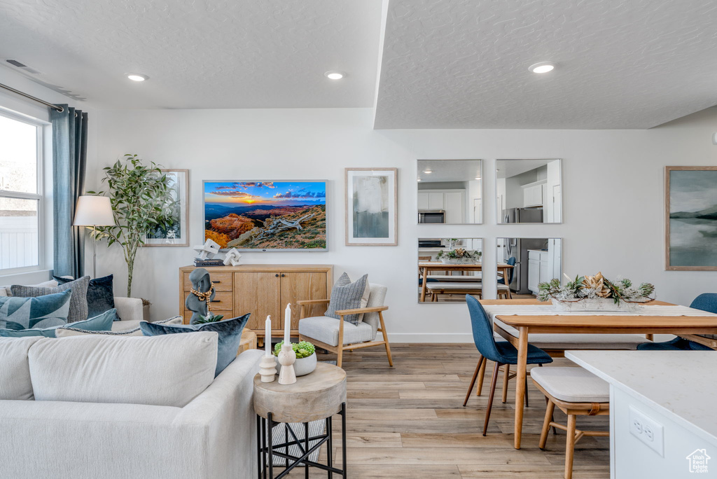 Living area with light wood-type flooring, a textured ceiling, recessed lighting, and baseboards