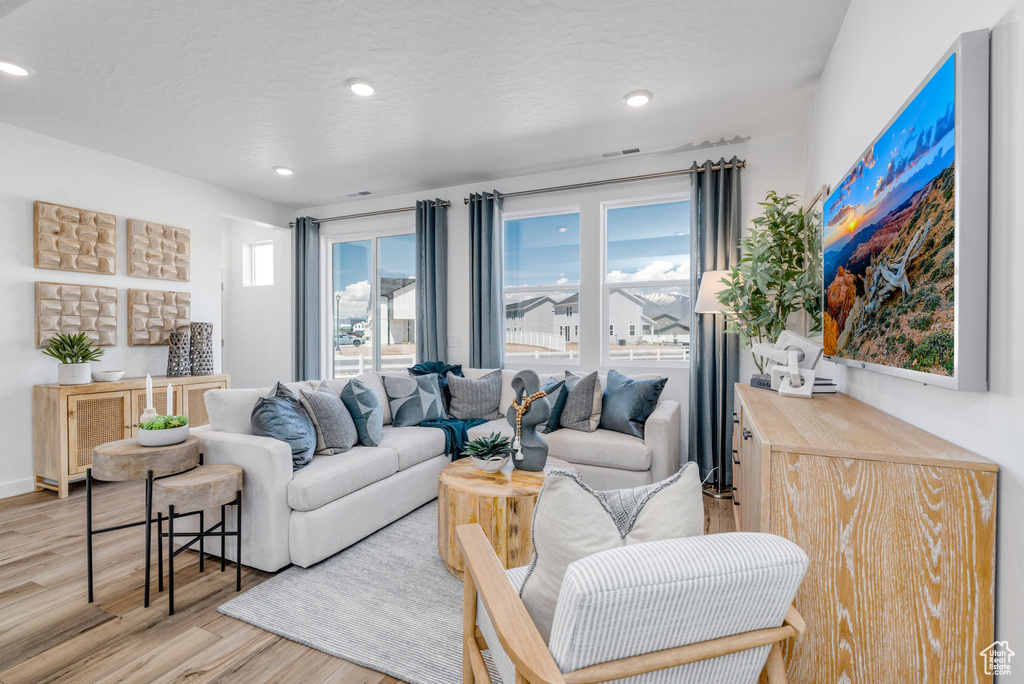 Living area with light wood-style floors and recessed lighting