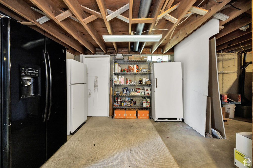Basement with freestanding refrigerator and black fridge
