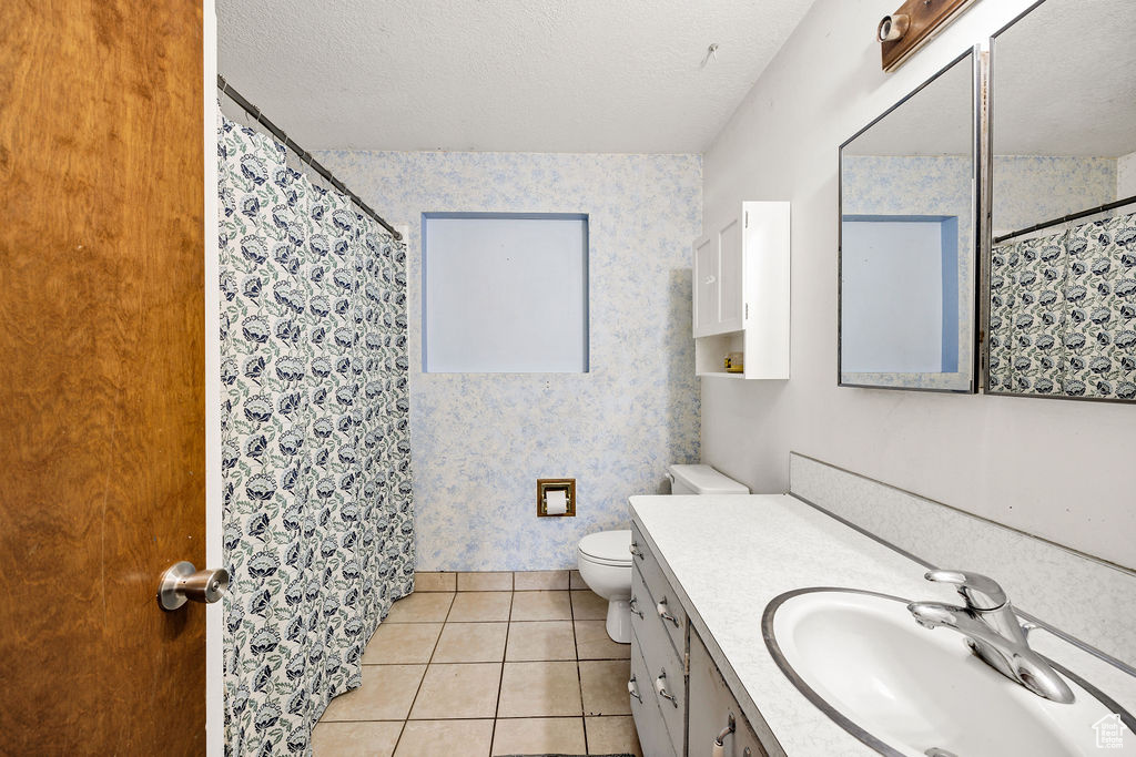 Bathroom with wallpapered walls, toilet, vanity, tile patterned floors, and a shower with shower curtain