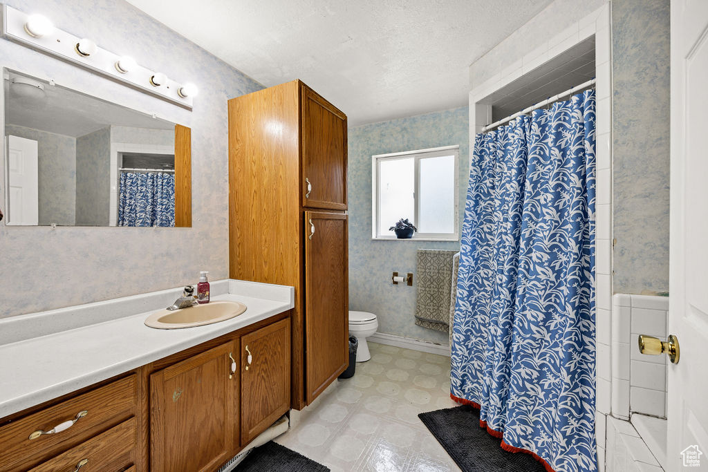 Bathroom featuring vanity, toilet, tile patterned floors, wallpapered walls, and curtained shower