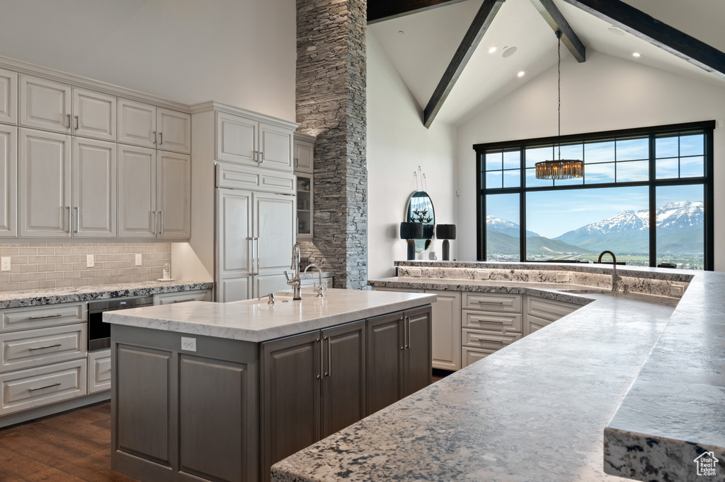Kitchen with a sink, high vaulted ceiling, wall oven, beamed ceiling, and white cabinetry
