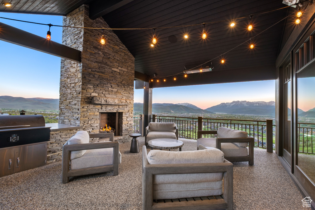 Patio terrace at dusk with a mountain view, an outdoor living space with a fireplace, and a grill