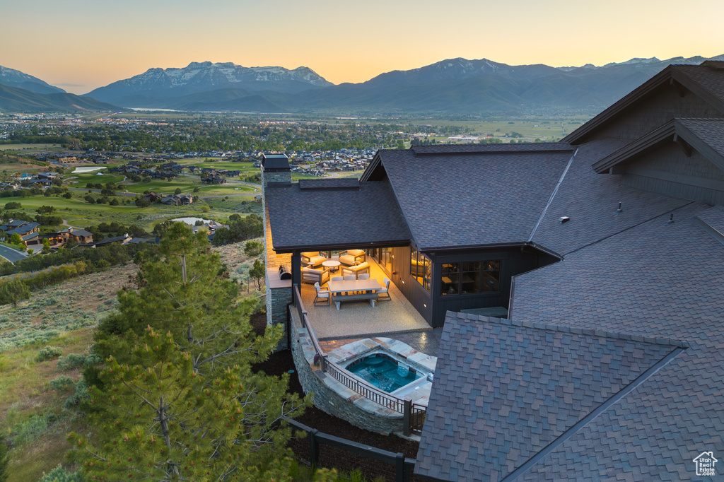 Pool at dusk featuring a mountain view and outdoor lounge area