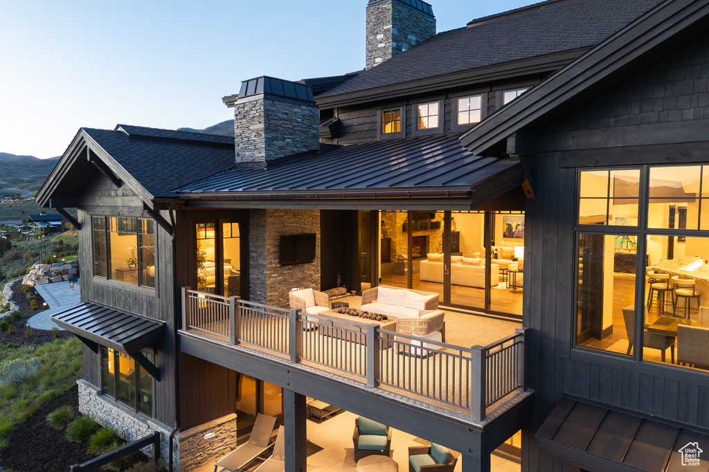 Back of property with a standing seam roof, a chimney, a shingled roof, metal roof, and a deck with mountain view