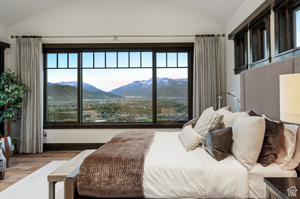 Bedroom featuring lofted ceiling, a mountain view, wood finished floors, and multiple windows