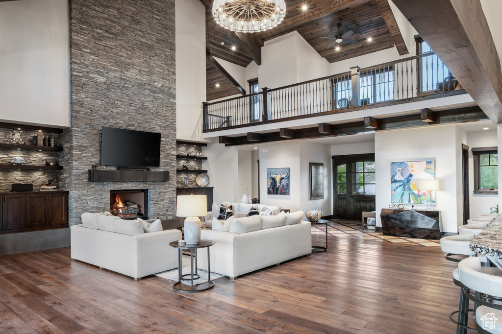 Living room with high vaulted ceiling, a stone fireplace, and wood-type flooring