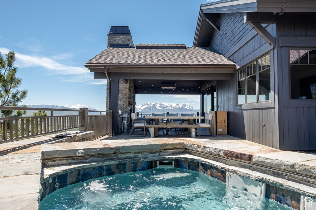 View of swimming pool with an outdoor hot tub, a mountain view, and a patio area
