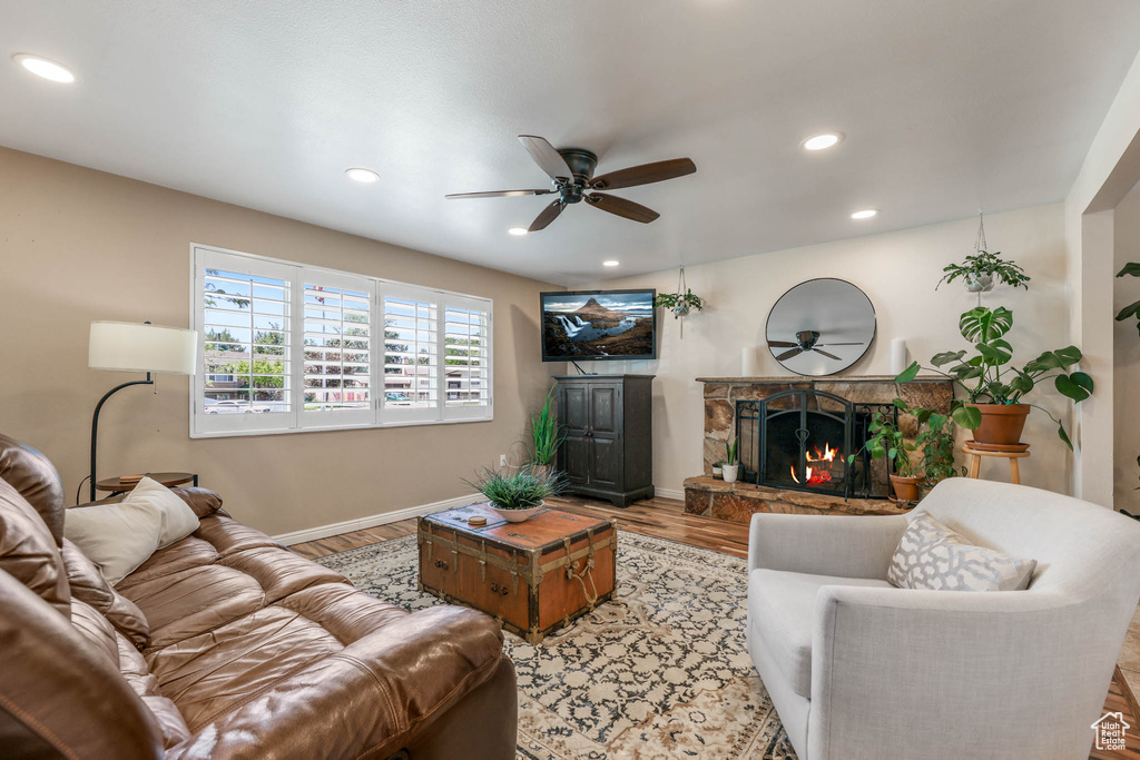 Living area featuring ceiling fan, a fireplace, wood finished floors, baseboards, and recessed lighting