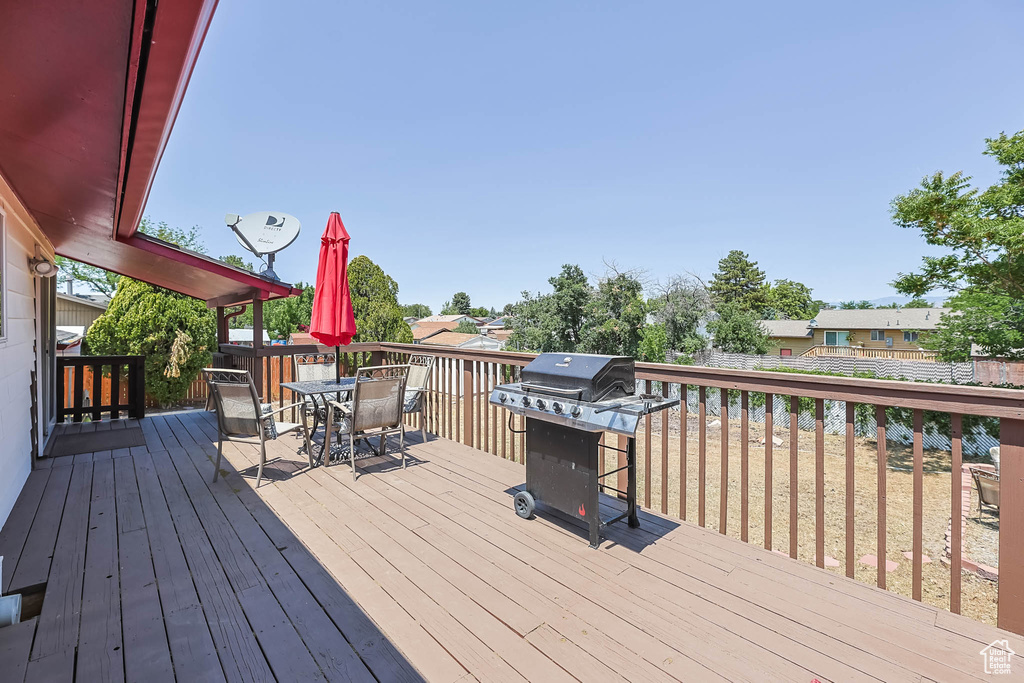 Wooden terrace featuring outdoor dining area and a grill