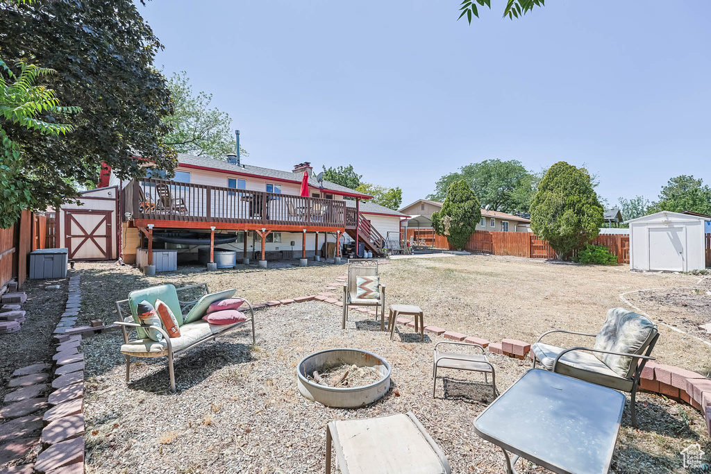 Fenced backyard with an outdoor fire pit, stairs, and a wooden deck