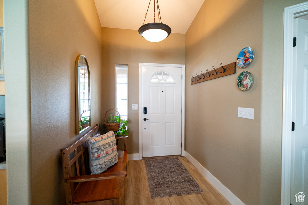 Foyer entrance featuring light wood-style floors, baseboards, and vaulted ceiling