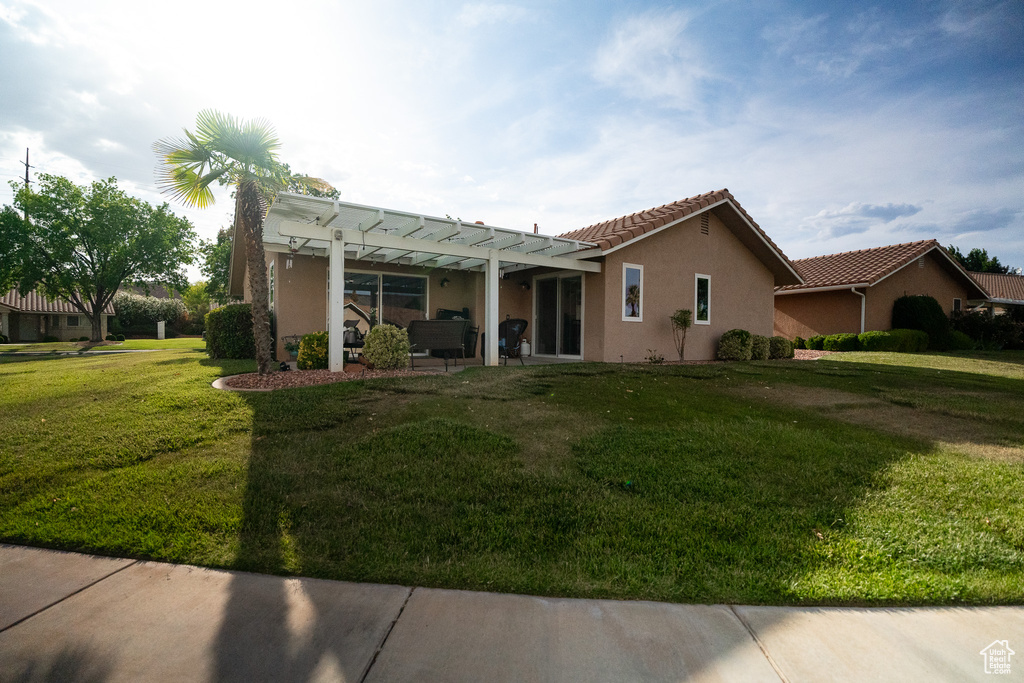 View of front of property featuring a pergola, stucco siding, a front yard, a tiled roof, and a patio
